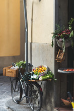 A Bicycle Parked Outside A Store Loaded With Veggies And Fruits