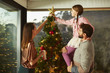 © ALTO IMAGES/Stocksy - Family Putting Star On Top Of Christmas Tree At Home