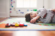 © Goodness Grace Photography/Stocksy - Young girl lying on floor playing with toy cars