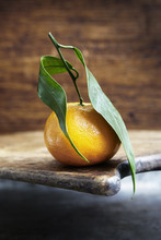 A Clementine With Leaves On A Wooden Board