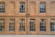 © Guille Faingold/Stocksy - Frontal view of factory facade with a lot of windows