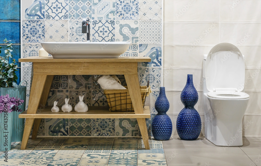 Modern spacious bathroom with bright tiles with toilet and sink. Side view