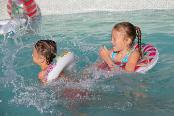 Canvas Print - Two happy children playing on the swimming pool at the day time.