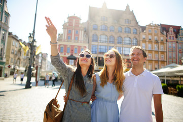 three young people stand on the square of the ancient city.