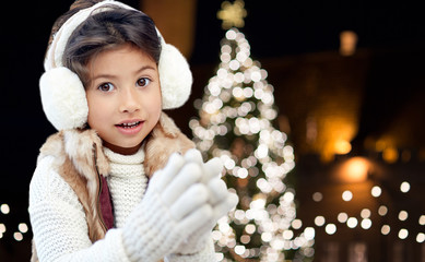 Wall Mural - happy girl wearing earmuffs over christmas lights