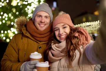 Canvas Print - couple with coffee taking selfie at christmas