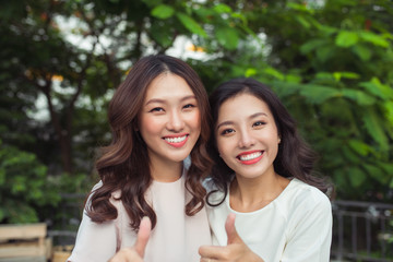 Happy young women friends well-dressed smiling while standing together