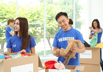 Wall Mural - Team of teen volunteers collecting donations in cardboard boxes indoors