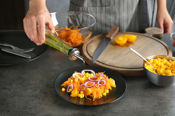 Wall Mural - Woman pouring oil on carrot salad in kitchen