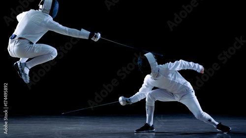 Obrazy Szermierka  dwoch-zawodowych-szermierzy-pokazuje-mistrzowskie-umiejetnosci-walki-mieczem-w-swojej-walce-w-folie-unikaja-skacza