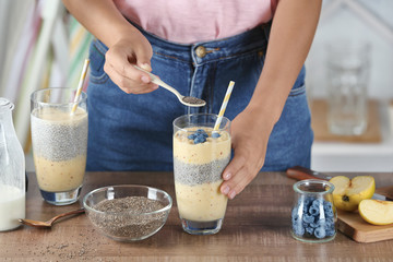 Poster - Young woman preparing smoothie with chia seeds on table in kitchen