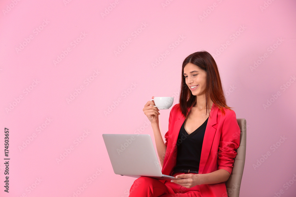 Young woman with laptop on color background