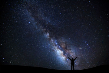 Wall Mural - landscape with milky way, night sky with stars and silhouette of a standing sporty man with raised u