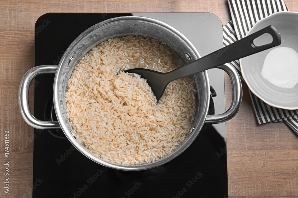 Saucepan with brown rice and spoon on stove