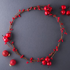 Wall Mural - frame with christmas wreath, berries and balls on dark background top view. merry christmas greeting