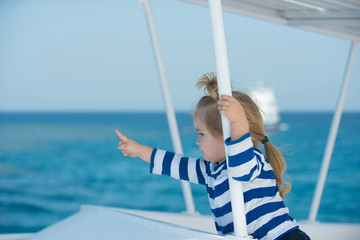 Wall Mural - Boy child with serious face sailing in white yacht