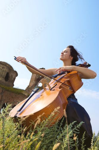 Plakat Dziewczyna gra na wiolonczeli na tle nieba