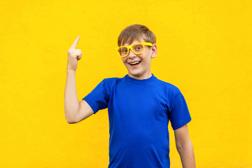 Young freckled boy has an idea, pointing with finger up isolated on yellow  wall background. Excited guy with solution for a problem.