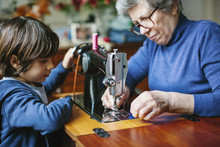Grandson Watching His Grandmother Working On A Sewing Machine