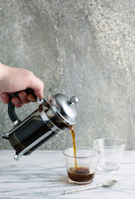 Hand Pouring Coffee From A Cafetiere Into A Glass.