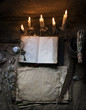 Magic fairytale table in the hut with window to the garden with open ancient book and burning candles