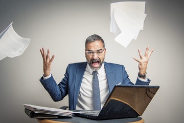 Enraged angry business man yelling and throwing papers and documents, making a mess of his office