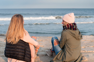 Friends. Two girls looking at sea on the beach in autumn.