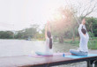 © Fluky - Asian men and women meditate and yoga at the waterfront on a wooden bridge for good health.