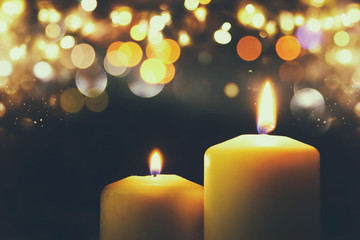 Burning candles over black background with bokeh glitter lights