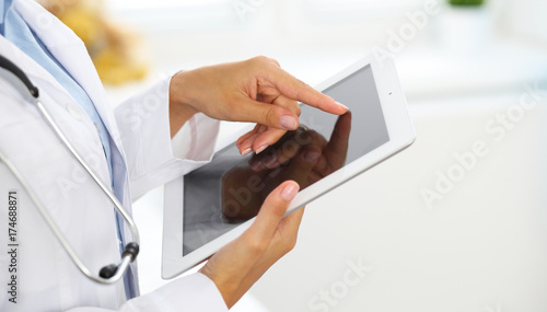 Plakat Kobiety doktorski używa pastylka komputer podczas gdy stojący prosto w szpitalu
