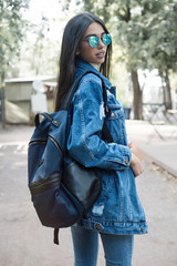 Wall Mural - Pretty stylish woman in fall casual outfit walking in city. Street style.Close up image of fashion details, jeans jacket, stylish bag.