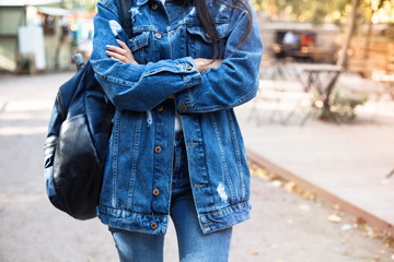 Wall Mural - Fashionable young woman in jeans, long jeans jacket and handbag on the city streets. Fashion.Stylish .