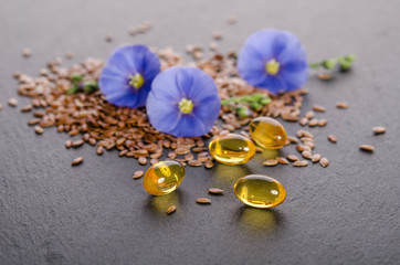 Wall Mural - Flax seeds , beauty flower and oil in caps on a grey background. Phytotherapy.