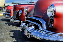 Three Heavy Front End Red Vintage Cars Lined Up  In A Row.