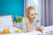 © ZoomTeam - Smiling young blond woman lying in the bed and eating a green salad