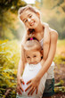 © svetabezu - Childhood, family, friendship and people concept - two happy kids sisters hugging outdoors.