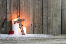 White Holiday Christmas Candles In Snow By Single Red Heart And Wooden Cross With Rustic Wood Background