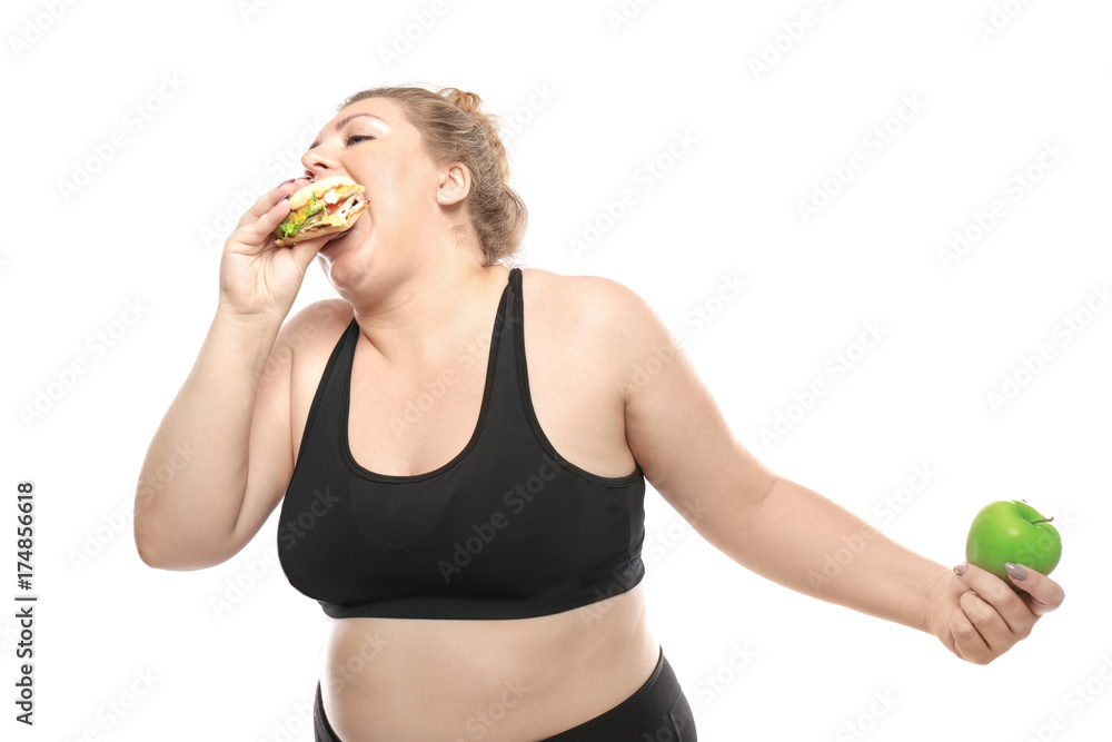 Overweight young woman with burger and apple on white background. Weight loss concept