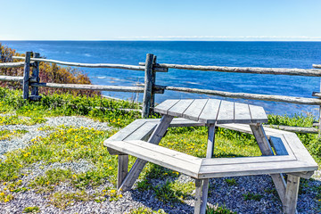 Wall Mural - Round wooden picnic table overlooking ocean or Saint Lawrence river in the Gaspe Peninsula, Quebec, Canada in Gaspesie region