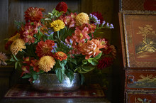 A Rsutic Country Flower Arrangement Beside A Red And Orange Antique Chinese Cabinet