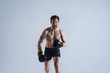 © Anatoliy Karlyuk - Picture of determined aggressive European boxer wearing black shorts and rubber gloves screaming, demonstrating that he can beat anyone. Aggressive male kickboxer training at white studio wall