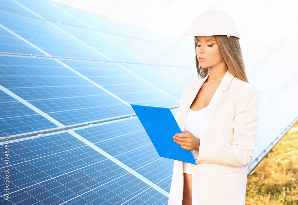 Female engineer developing project on installation of solar panels outdoors