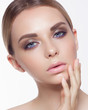 The young woman touches a face, showing gentle care behind skin. Bright blue eyes with a bright gentle make-up, chubby lips. Spa, cosmetology, ijektion