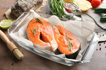 Poster - Fresh salmon steaks in baking dish on wooden table