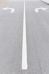 Wall Mural - White arrow signs painted on road as direction restriction. Arrow signs as road markings on a street with two lanes