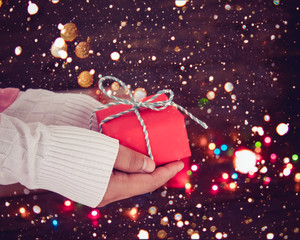 Wall Mural - Woman hands holding Christmas handmade gift box with snow and bokeh light background. vintage color tone