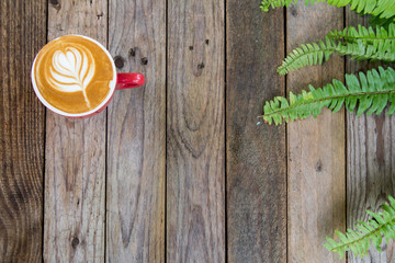 Wall Mural - coffee cup on table with fern leaf background