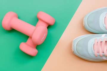 sport, healthy lifestyle and objects concept - close up sport shoes and dumbbells on green and orange background. Concept healthy lifestyle, sport and diet. Sport equipment. Copy space. Top view.