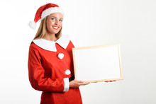 Smiling Blonde Woman In Santa Claus Clothes With White Board