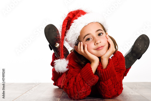 Zdjęcie XXL Urocza mała dziewczynka jest ubranym Santa kapelusz kłaść na drewnianej podłoga